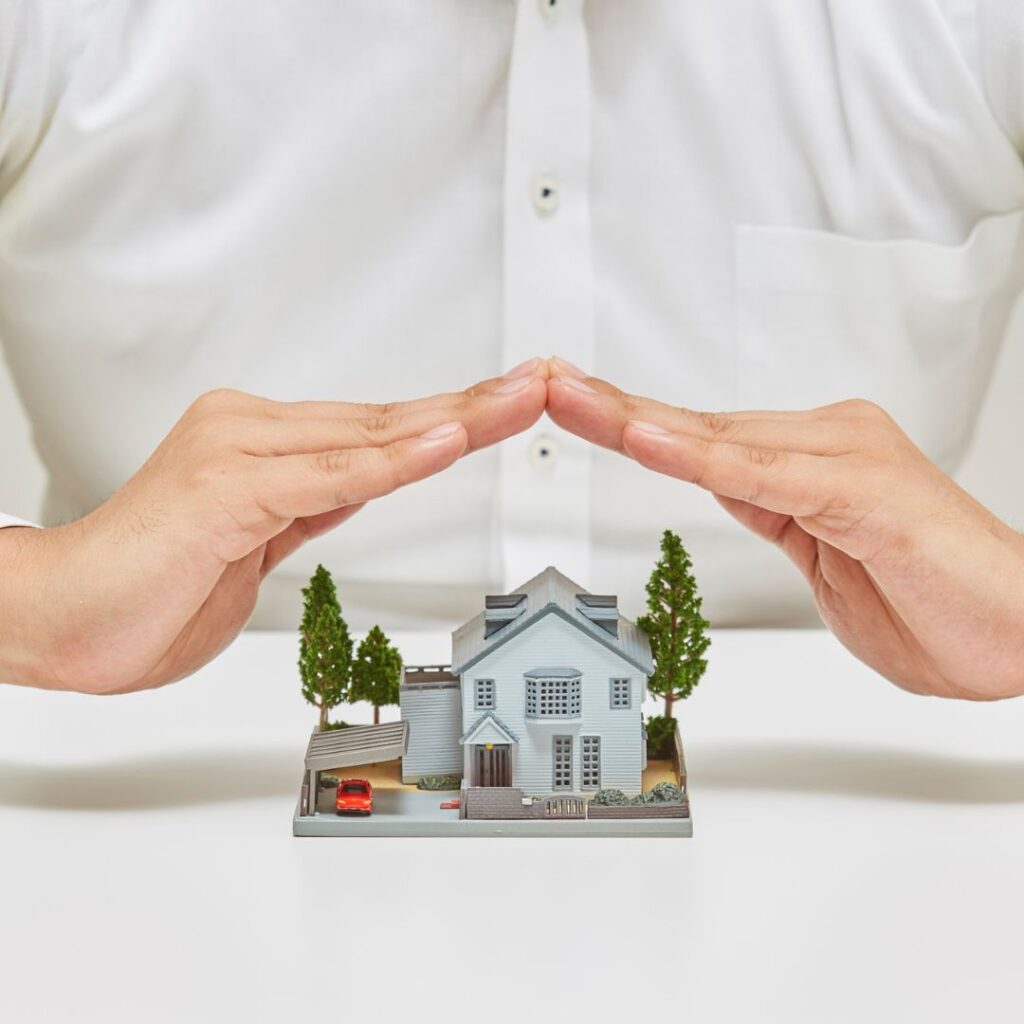 mains protégeant une maquette de maison, construire ou acheter en VEFA Luxembourg