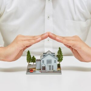 mains protégeant une maquette de maison, construire ou acheter en VEFA Luxembourg