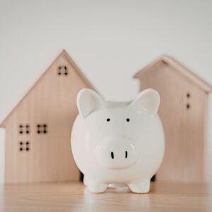 tirelire blanche devant des maisons en bois aides au logement et TVA à 3 % Luxembourg